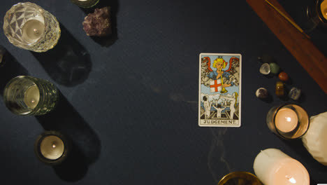 Overhead-Shot-Of-Person-Giving-Tarot-Card-Reading-Laying-Down-The-Judgement-Card-On-Table